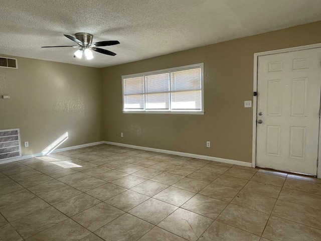 spare room with light tile patterned flooring, ceiling fan, and a textured ceiling