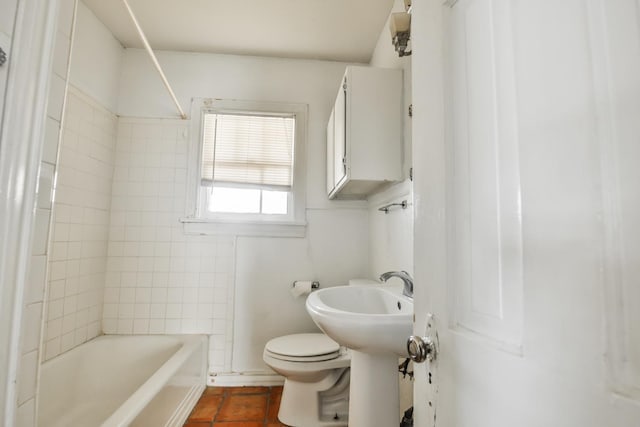 bathroom featuring tiled shower / bath, tile patterned floors, and toilet