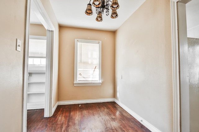 interior space featuring dark wood-type flooring, plenty of natural light, and an inviting chandelier