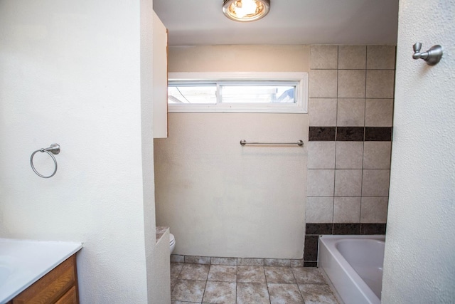 bathroom with a washtub, vanity, tile patterned floors, and toilet