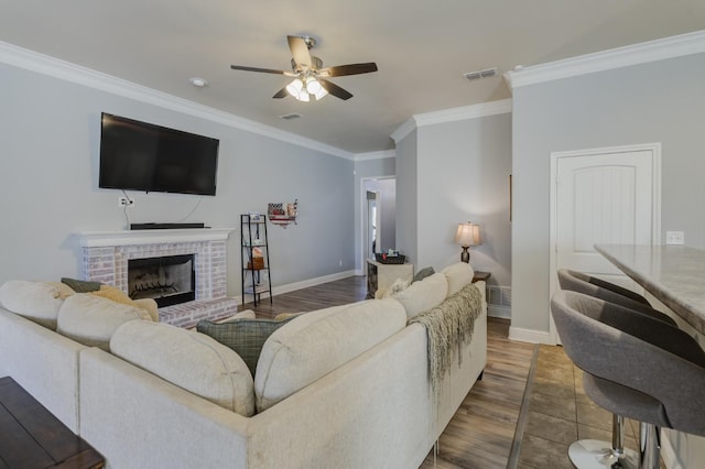 living room with ornamental molding, dark wood-type flooring, ceiling fan, and a fireplace