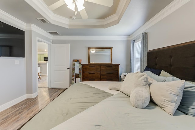 bedroom with crown molding, light hardwood / wood-style floors, a raised ceiling, and ceiling fan