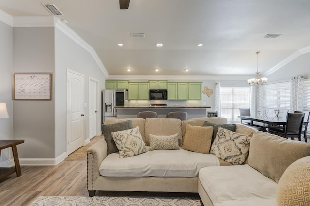 living room with ornamental molding, a chandelier, vaulted ceiling, and light hardwood / wood-style flooring