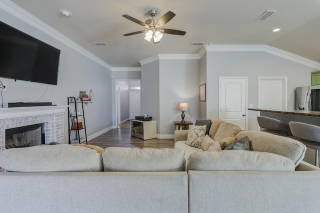 living room with lofted ceiling, crown molding, dark wood-type flooring, ceiling fan, and a fireplace