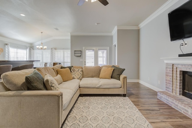 living room featuring a fireplace, ornamental molding, light hardwood / wood-style floors, ceiling fan with notable chandelier, and vaulted ceiling