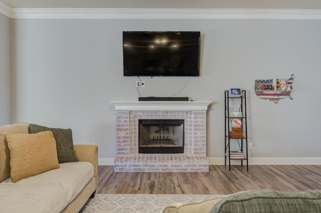 living room with ornamental molding, wood-type flooring, and a brick fireplace