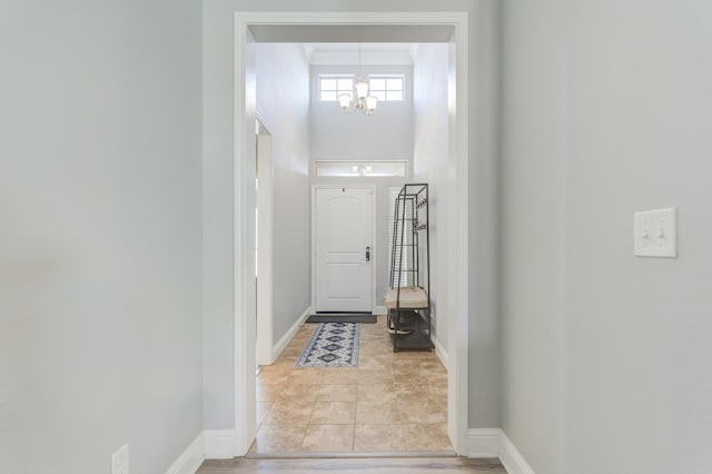 entryway featuring light tile patterned floors, a towering ceiling, and a chandelier