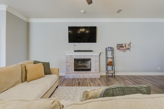 living room featuring wood-type flooring, ornamental molding, ceiling fan, and a fireplace