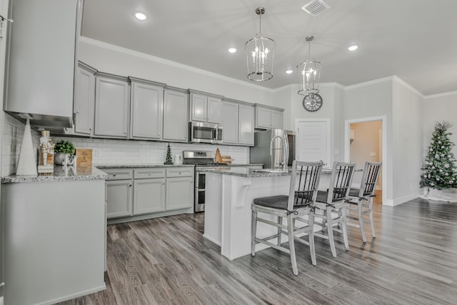 kitchen featuring stainless steel appliances, an island with sink, and gray cabinetry