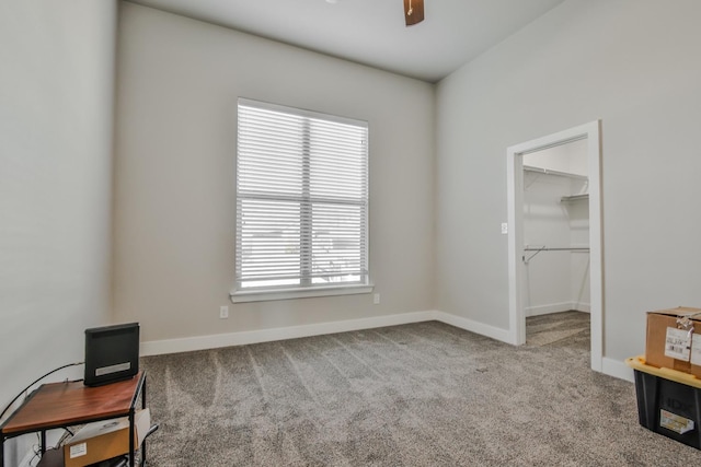 interior space with ceiling fan, a walk in closet, and light carpet