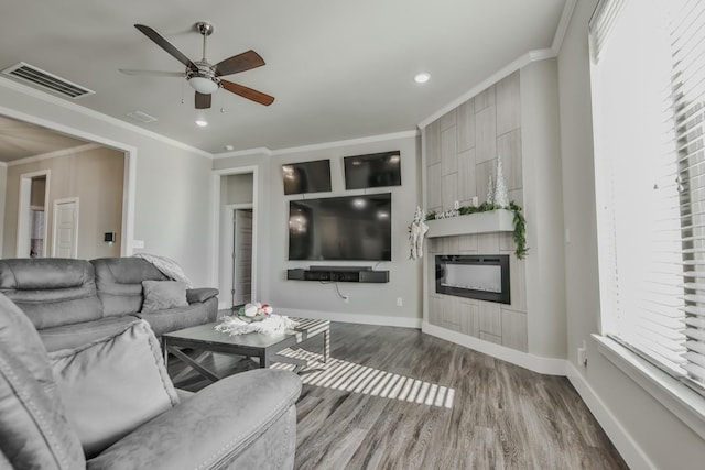 living room with hardwood / wood-style flooring, crown molding, a large fireplace, and ceiling fan