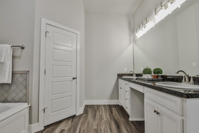 bathroom with hardwood / wood-style flooring, vanity, and a bath