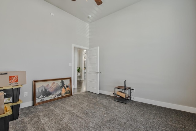 carpeted empty room featuring a towering ceiling and ceiling fan