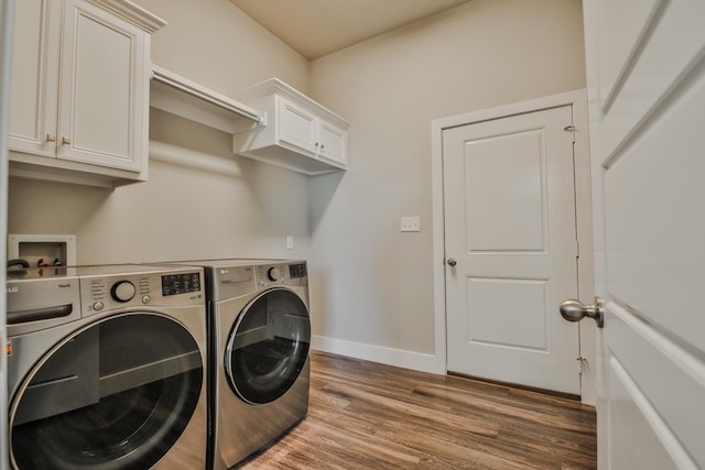 clothes washing area with cabinets, washer and dryer, and dark wood-type flooring