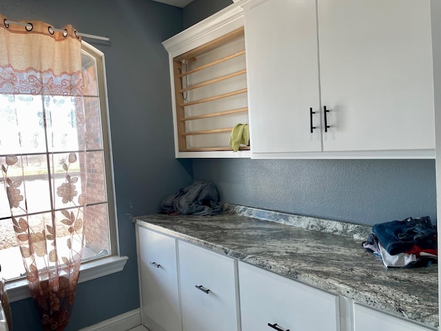 bar featuring stone counters and white cabinetry