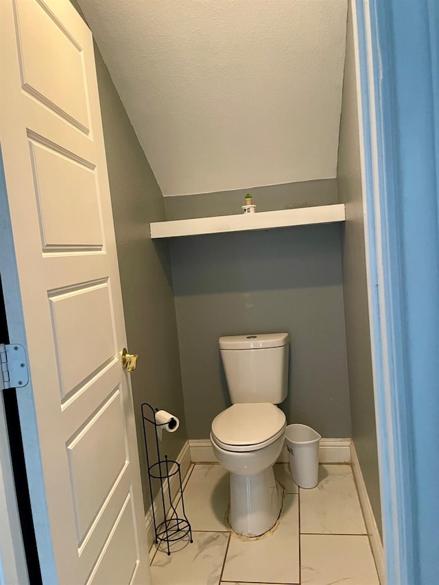 bathroom with lofted ceiling, a textured ceiling, and toilet