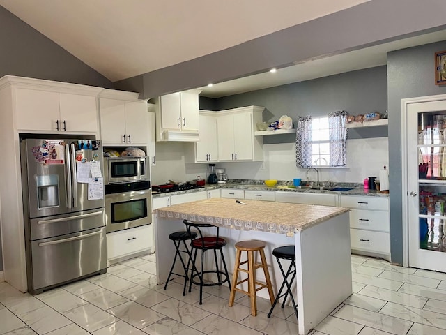 kitchen with a breakfast bar, sink, white cabinets, a center island, and stainless steel appliances