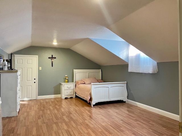 bedroom with vaulted ceiling and light hardwood / wood-style flooring