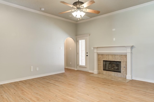 unfurnished living room featuring a tiled fireplace, crown molding, ceiling fan, and light hardwood / wood-style flooring