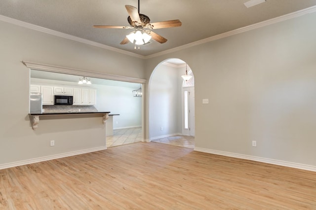 unfurnished living room featuring crown molding, ceiling fan, and light hardwood / wood-style floors