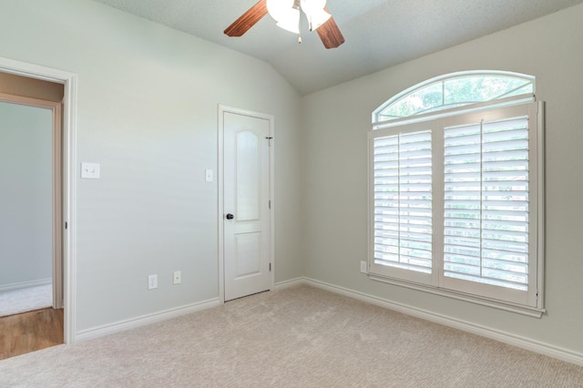 empty room featuring ceiling fan, light colored carpet, and lofted ceiling