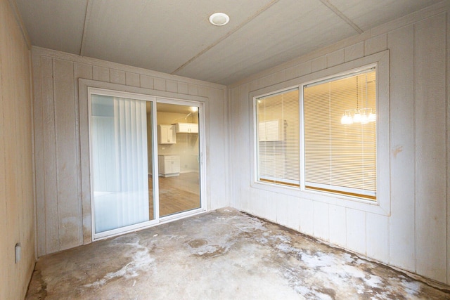 empty room featuring concrete flooring and wood walls