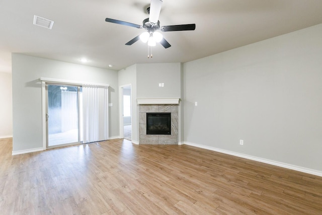 unfurnished living room featuring ceiling fan, a high end fireplace, visible vents, baseboards, and light wood finished floors