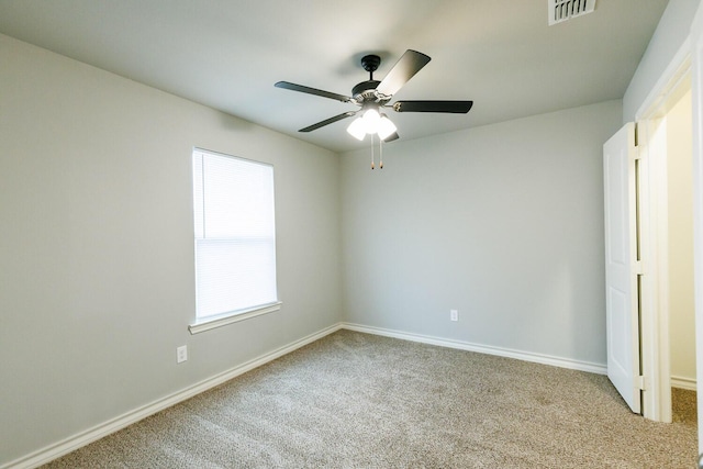 empty room featuring a ceiling fan, carpet, visible vents, and baseboards