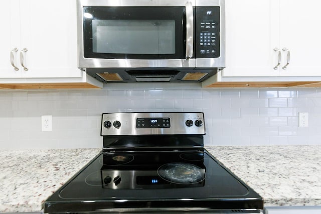 kitchen with stainless steel appliances, white cabinets, and tasteful backsplash