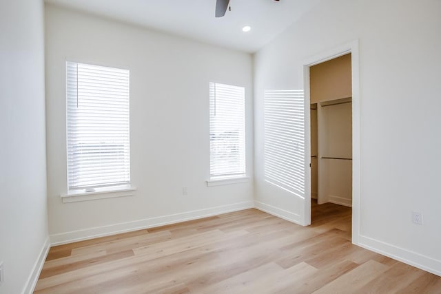 unfurnished bedroom featuring multiple windows, ceiling fan, a spacious closet, and light hardwood / wood-style floors