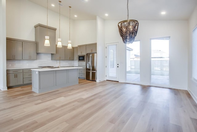 kitchen with stainless steel fridge, decorative light fixtures, light hardwood / wood-style floors, and black microwave