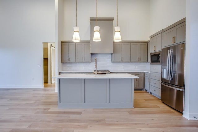 kitchen featuring a towering ceiling, tasteful backsplash, black microwave, hanging light fixtures, and stainless steel refrigerator with ice dispenser