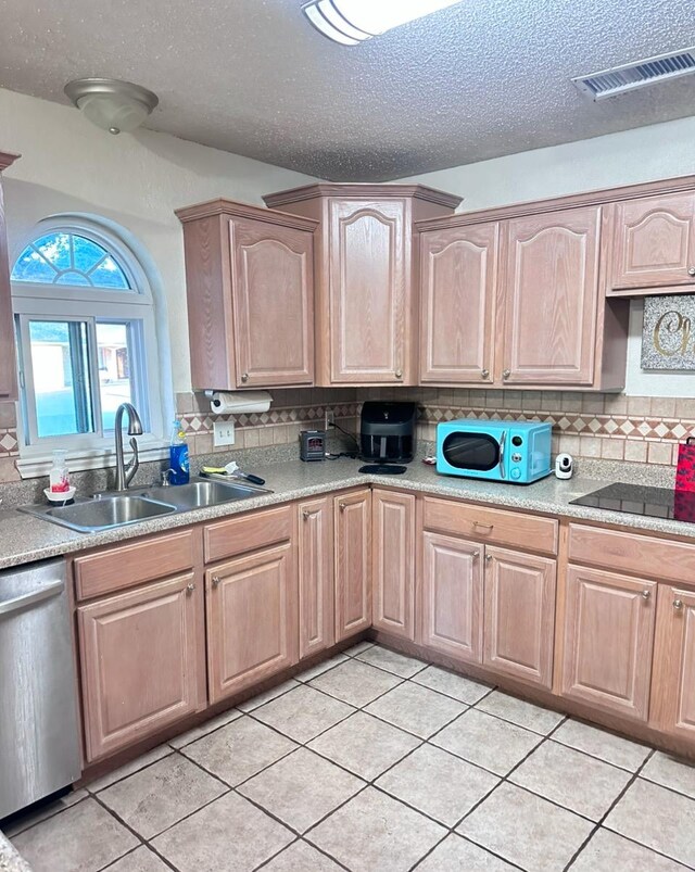 kitchen featuring tasteful backsplash, stainless steel dishwasher, sink, and a textured ceiling