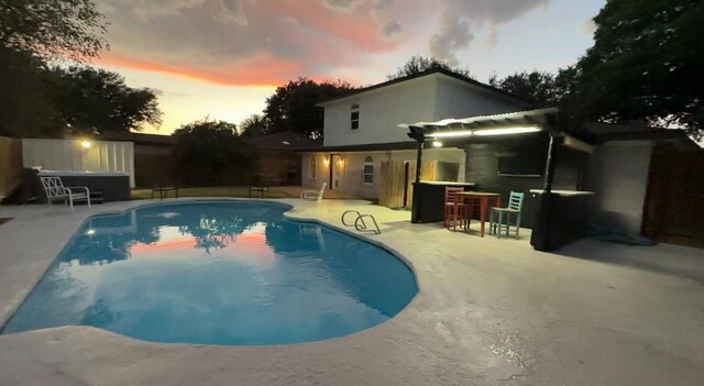 pool at dusk with a patio area