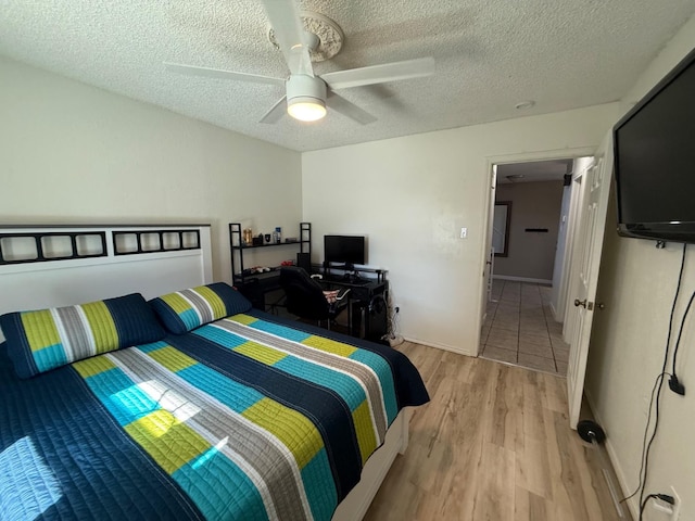 bedroom with ceiling fan, a textured ceiling, and light wood-type flooring