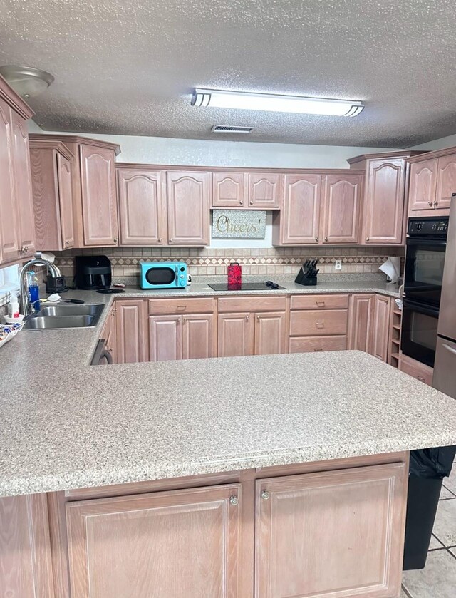 kitchen featuring tasteful backsplash, sink, black appliances, and a textured ceiling