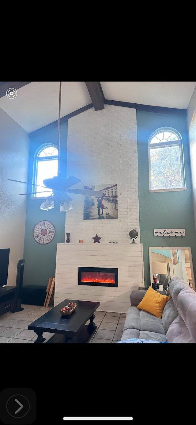 living room featuring light tile patterned floors, vaulted ceiling with beams, and a large fireplace