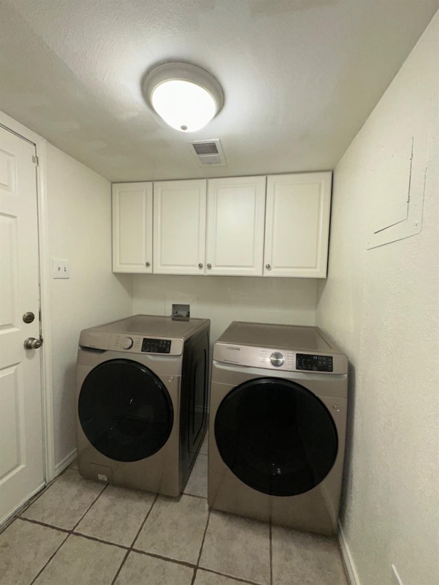 washroom featuring separate washer and dryer, cabinets, a textured ceiling, and light tile patterned flooring