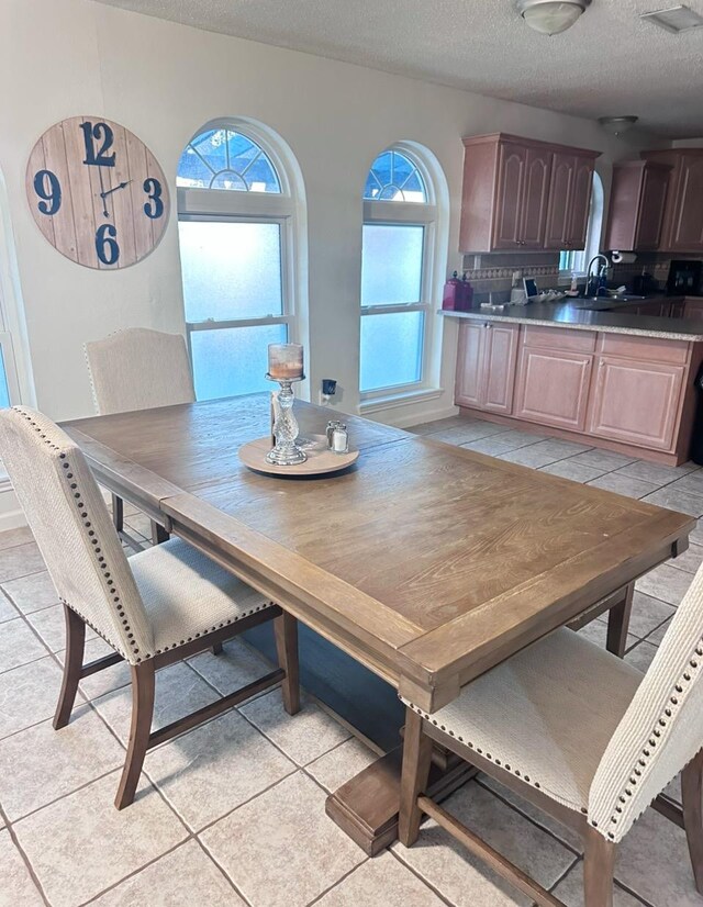 tiled dining area featuring sink and a textured ceiling