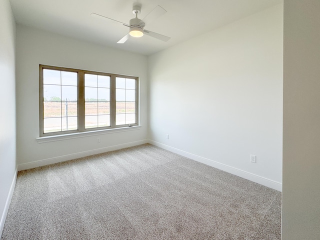 spare room with light carpet, a ceiling fan, and baseboards