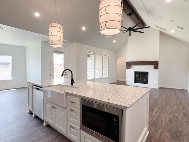 kitchen with a kitchen island with sink, stainless steel dishwasher, a sink, built in microwave, and visible vents