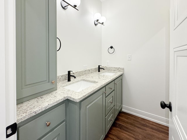 bathroom with wood finished floors, baseboards, a sink, and double vanity