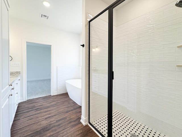 bathroom featuring visible vents, a freestanding tub, wood finished floors, a shower stall, and vanity