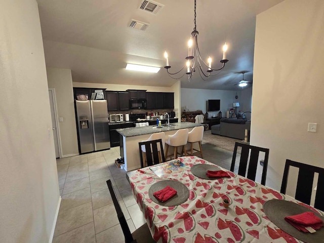 dining area featuring light tile patterned flooring, sink, and ceiling fan with notable chandelier