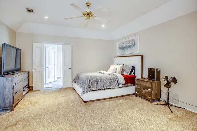 carpeted bedroom featuring a tray ceiling and ceiling fan