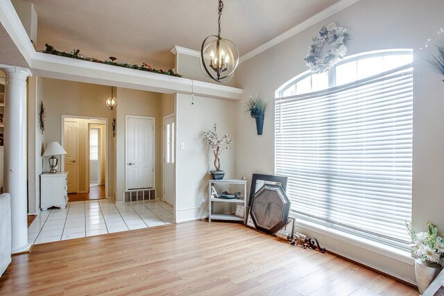 foyer with decorative columns, crown molding, a wealth of natural light, and light hardwood / wood-style floors