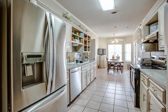 kitchen featuring light tile patterned flooring, appliances with stainless steel finishes, white cabinets, ornamental molding, and ceiling fan