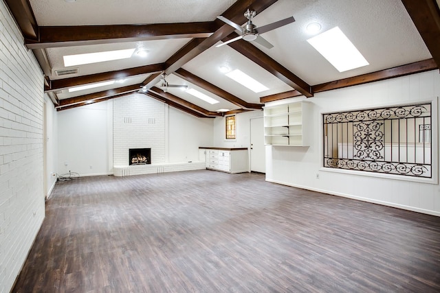 unfurnished living room with brick wall, lofted ceiling with beams, dark hardwood / wood-style flooring, ceiling fan, and a brick fireplace