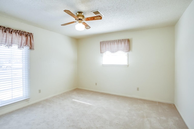 carpeted empty room featuring ceiling fan, a textured ceiling, and a healthy amount of sunlight