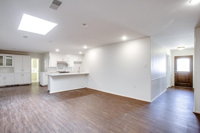 unfurnished living room featuring dark hardwood / wood-style floors and a skylight